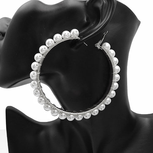 Oversized hoop earrings with pearl trim detailing along the outer edge on a mannequin ear display