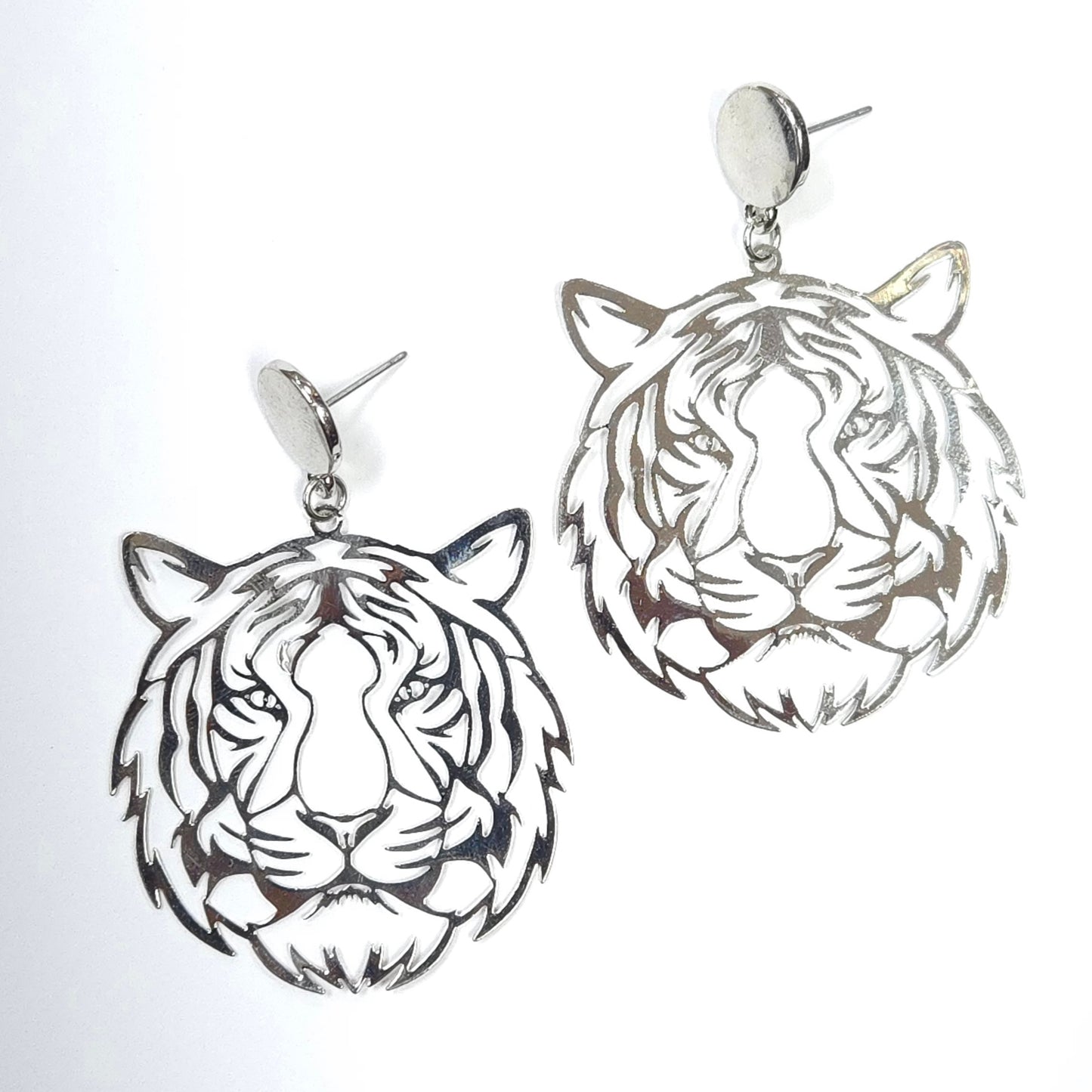 Silver tiger head earrings on a light gray background