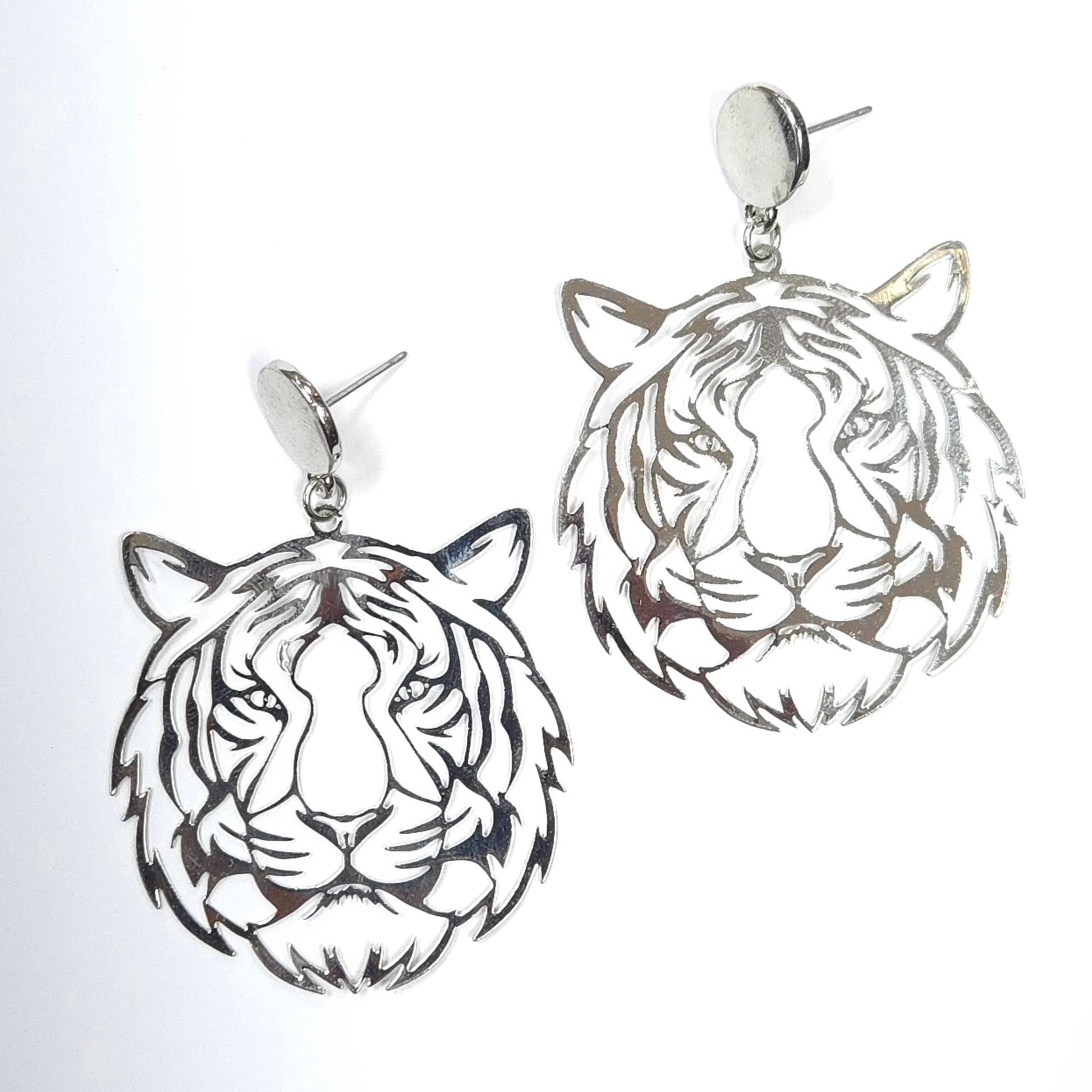 Silver tiger head earrings on a light gray background