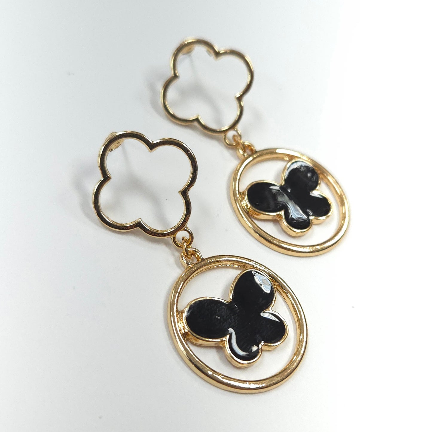 Gold and black clover-shaped earrings on a white background