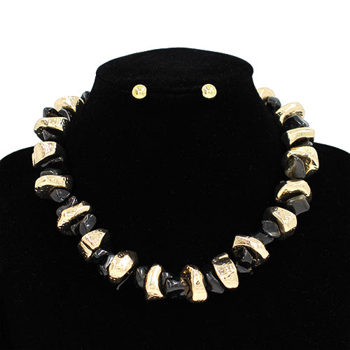 Black and gold necklace and earrings on a black stand