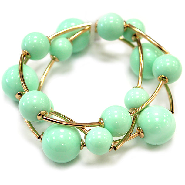 Layered coil bracelet with glossy round beads and gold tone curved metal accents in a modern wrap design.