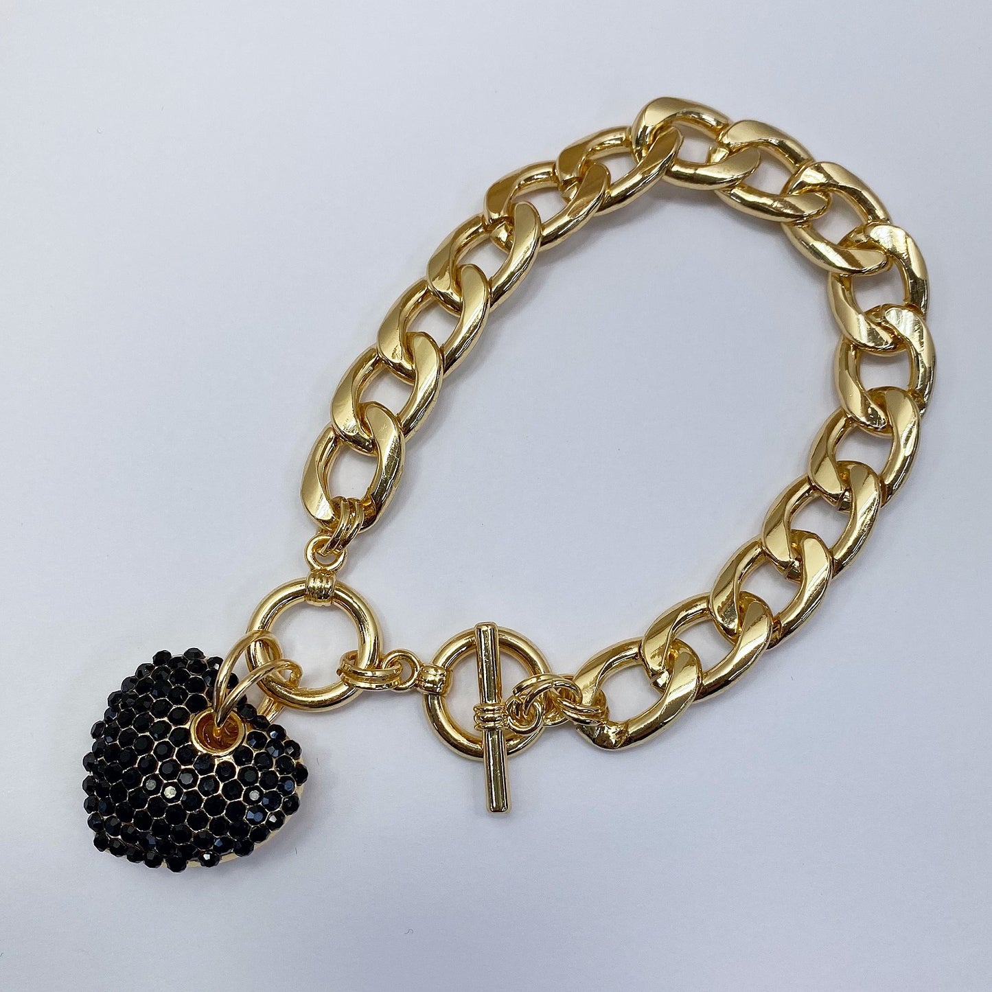 Gold chain bracelet with a black beaded charm on a white background