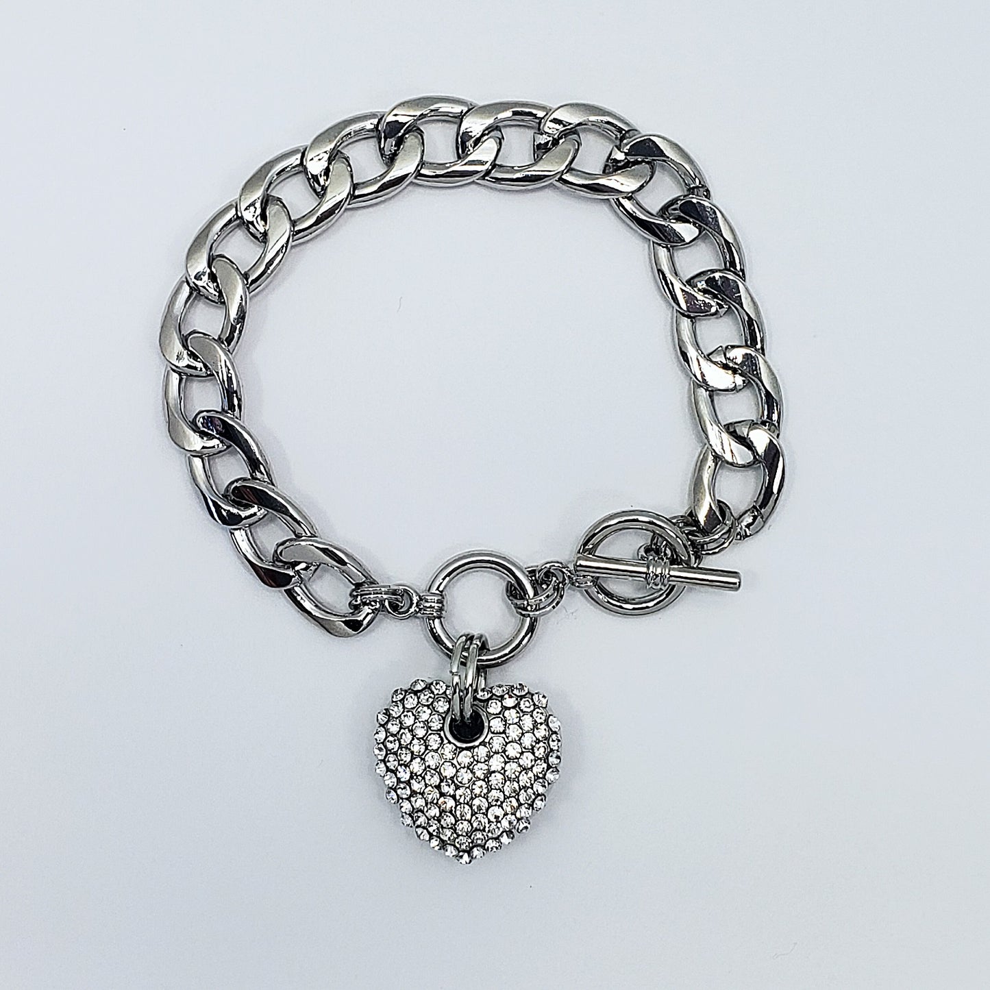 Silver chain bracelet with a heart-shaped charm on a light gray background