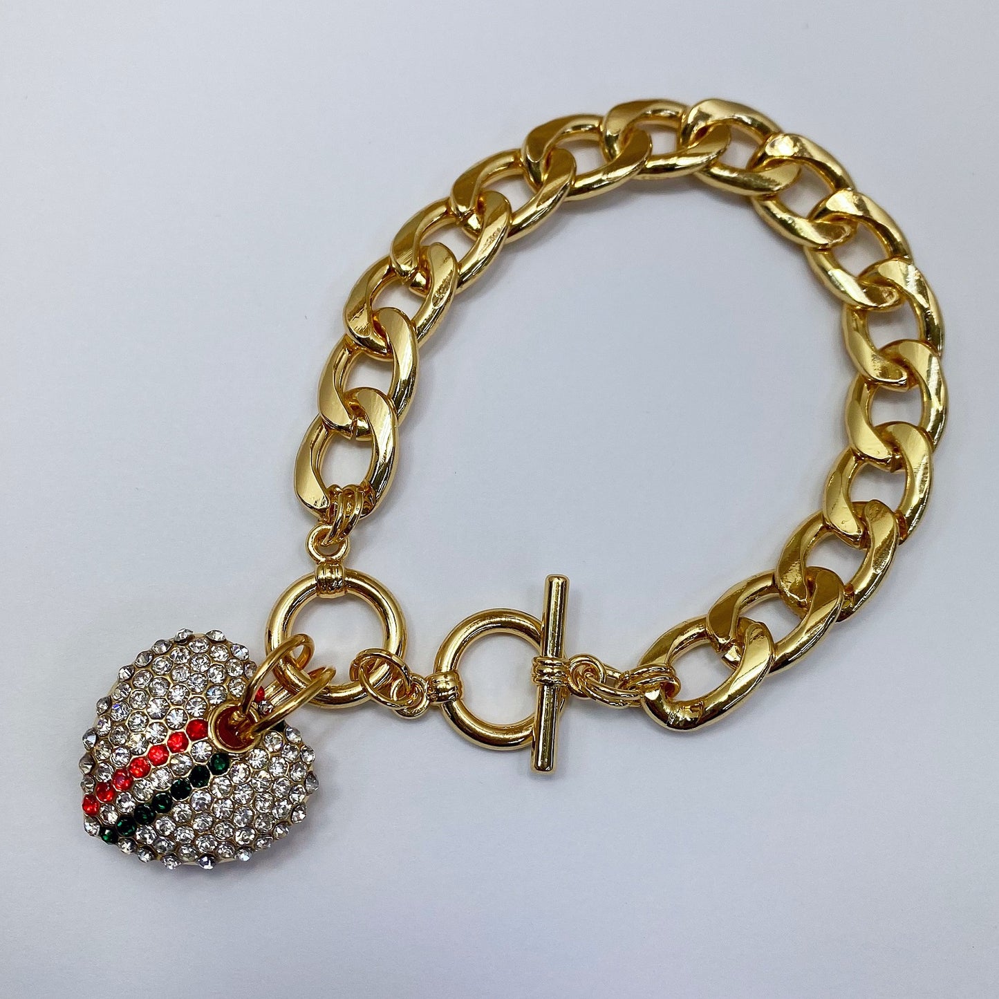 Gold chain bracelet with a decorative charm on a light gray background