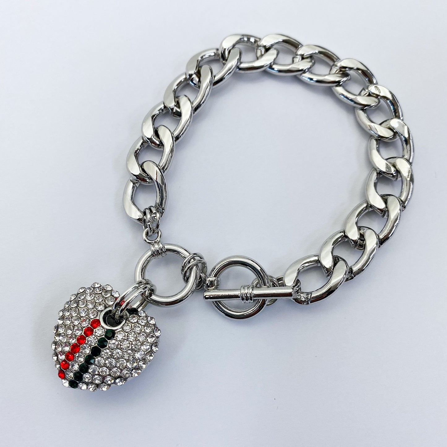 Silver chain bracelet with a heart-shaped charm on a light gray background