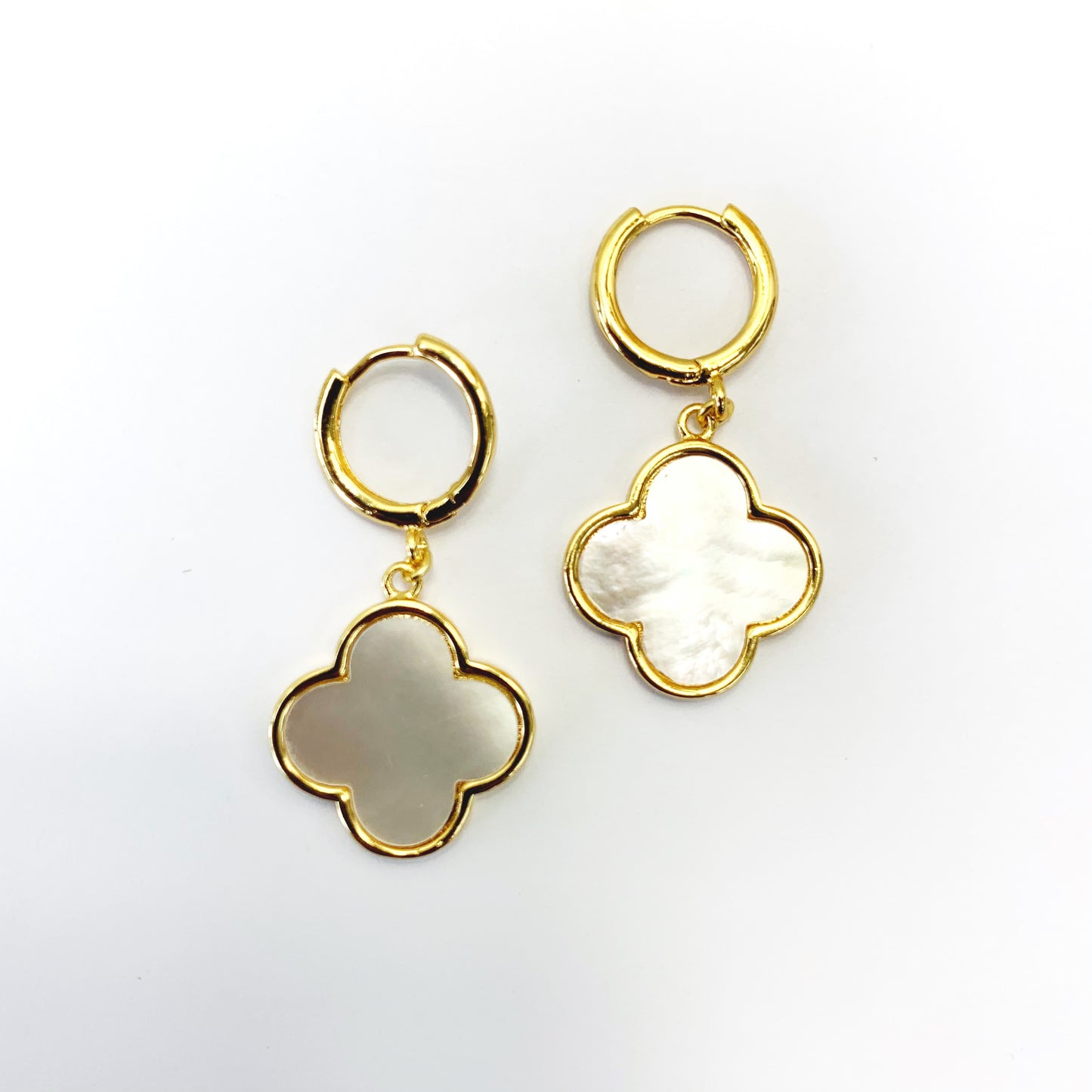Hoop earrings with clover-shaped drop charms and polished trim in a chic boutique fashion style.
