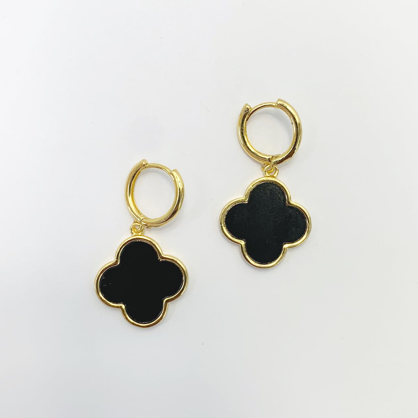 Hoop earrings with clover-shaped drop charms and polished trim in a chic boutique fashion style.