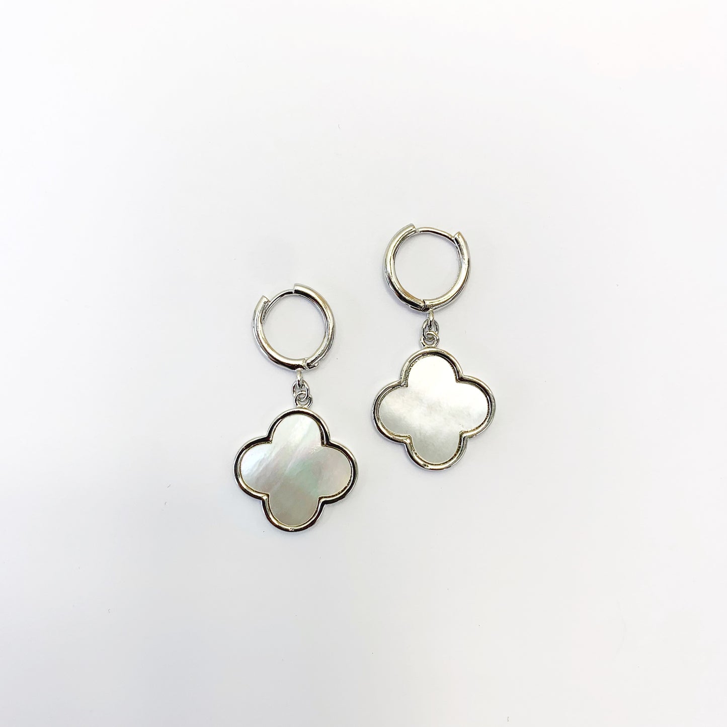 Hoop earrings with clover-shaped drop charms and polished trim in a chic boutique fashion style.