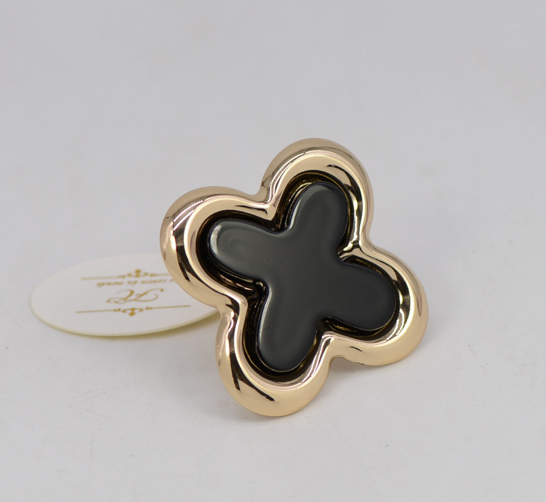 Gold and black clover-shaped object on a light gray background