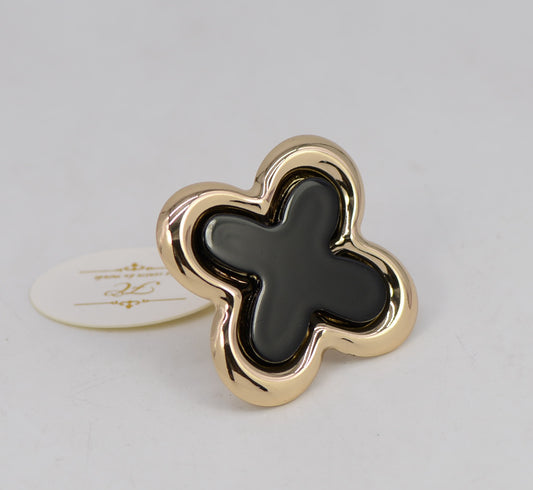 Gold and black clover-shaped object on a light gray background