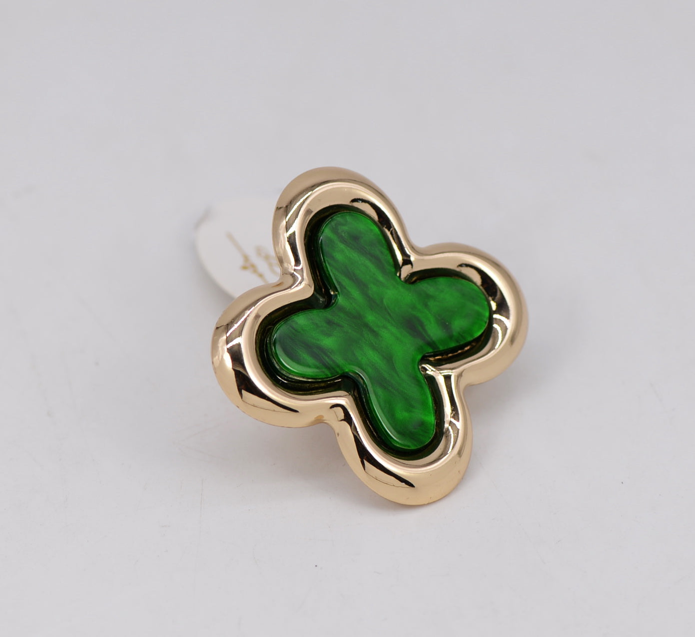 Gold ring with a green clover-shaped stone on a light gray background