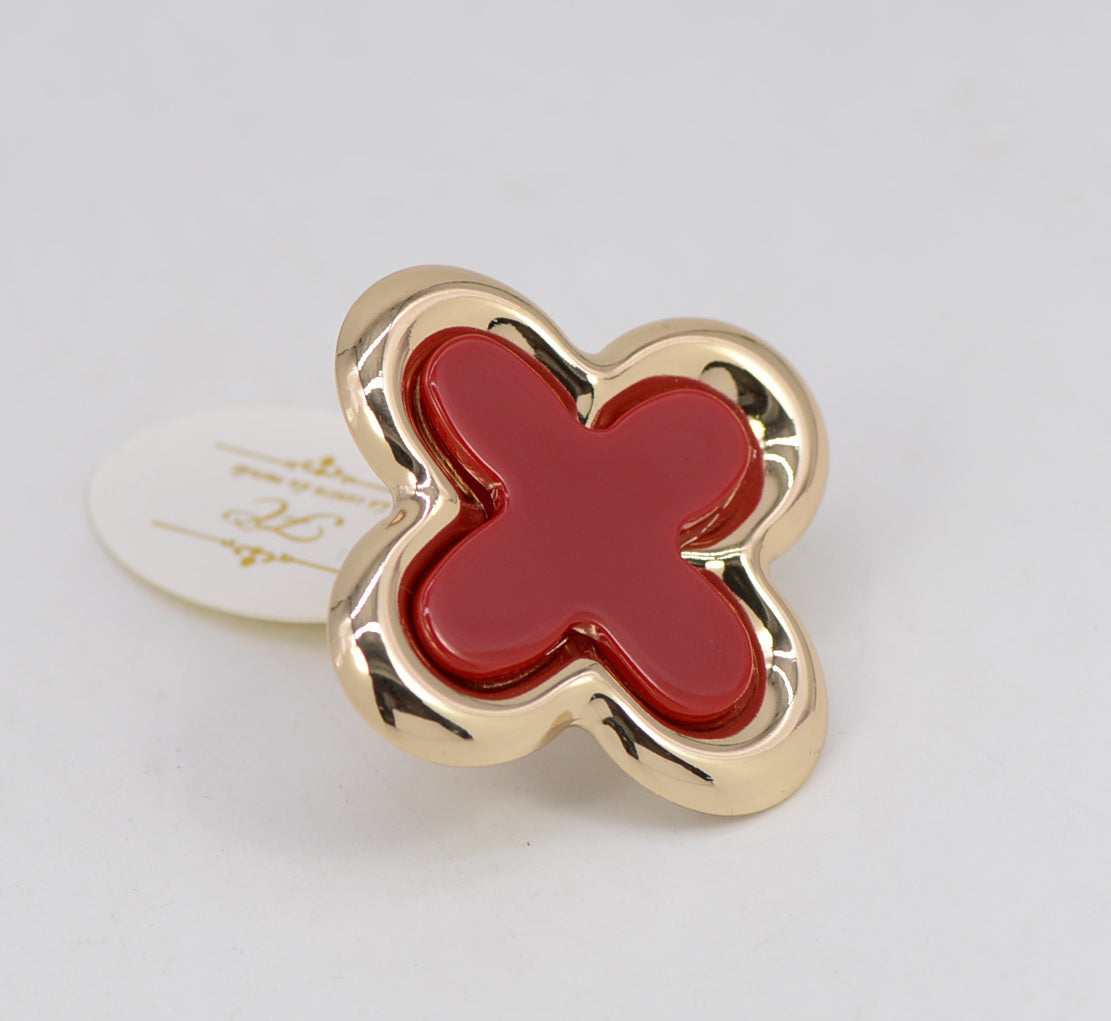 Gold butterfly-shaped object with red center on a light gray background
