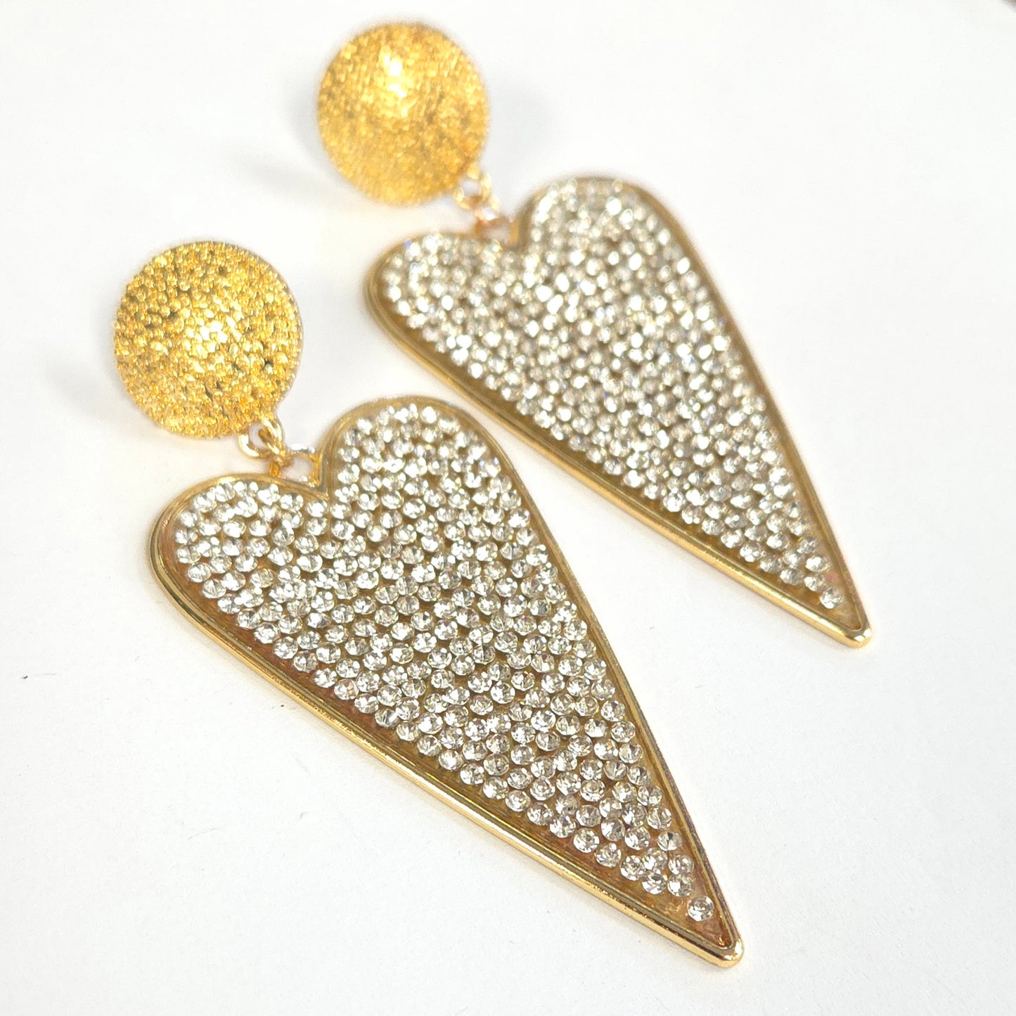 Gold heart-shaped earrings with rhinestone details on a white background