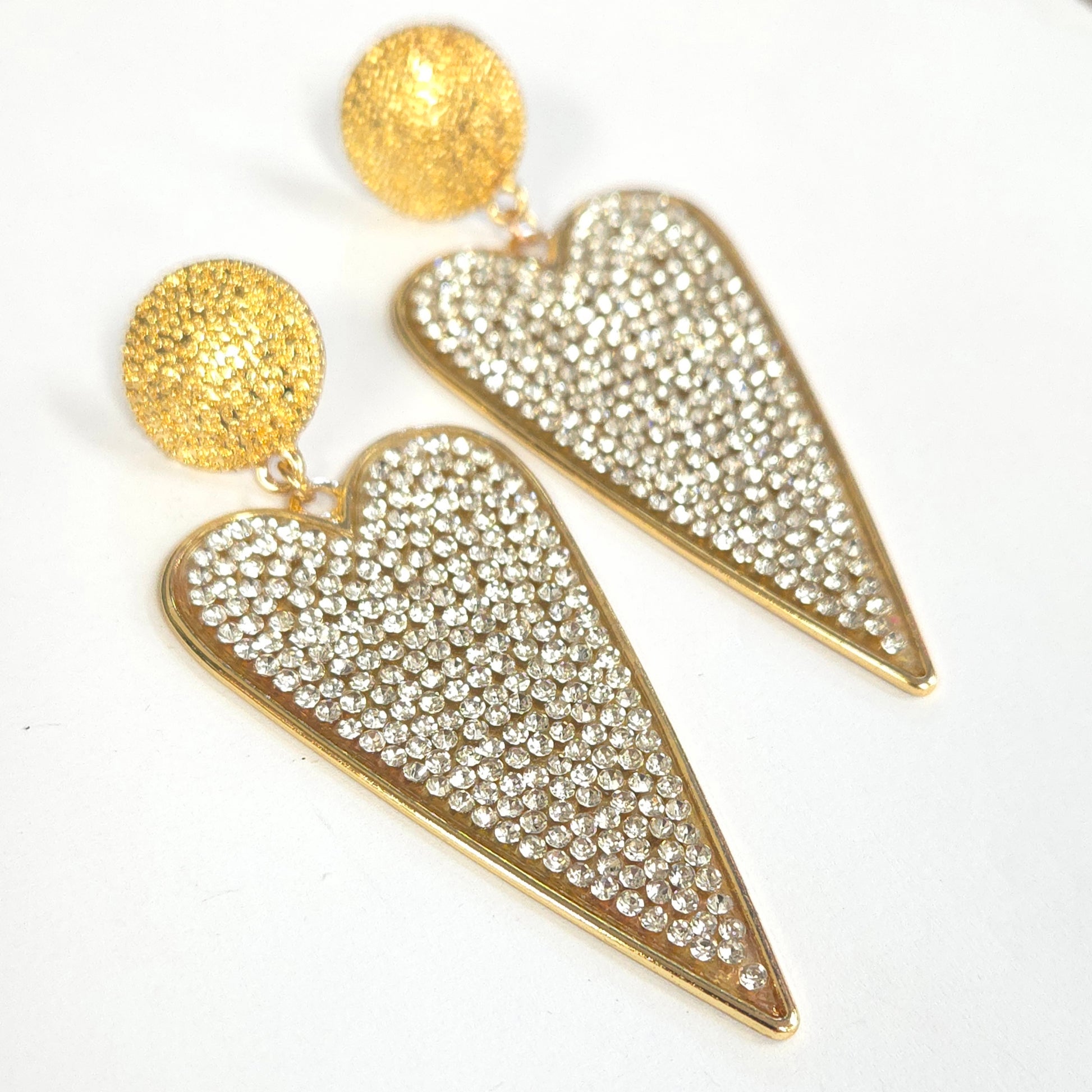 Gold heart-shaped earrings with rhinestone details on a white background