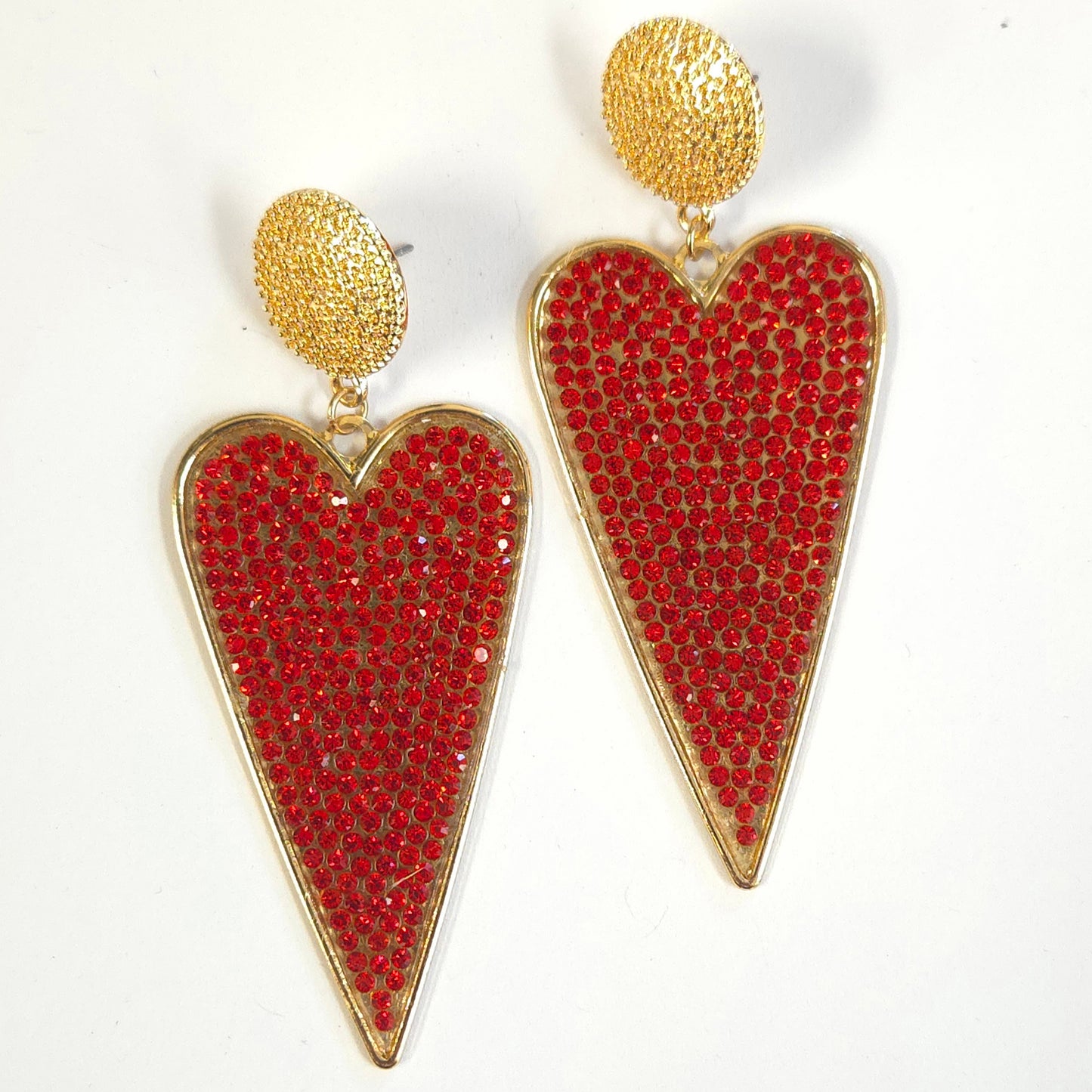 Heart-shaped earrings with red gemstones and gold accents on a white background
