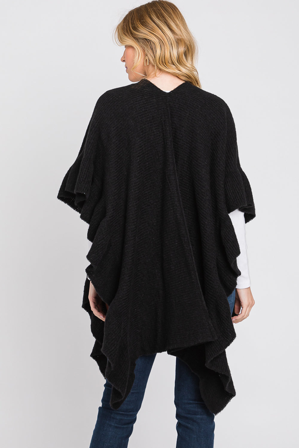 Woman wearing a black poncho against a white background