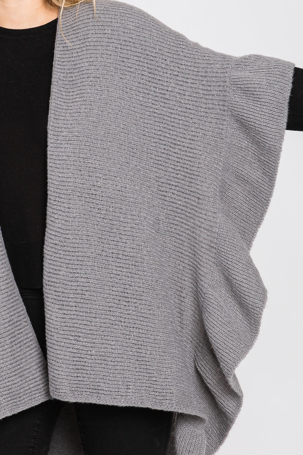 Gray knitted cardigan over a black top on a white background