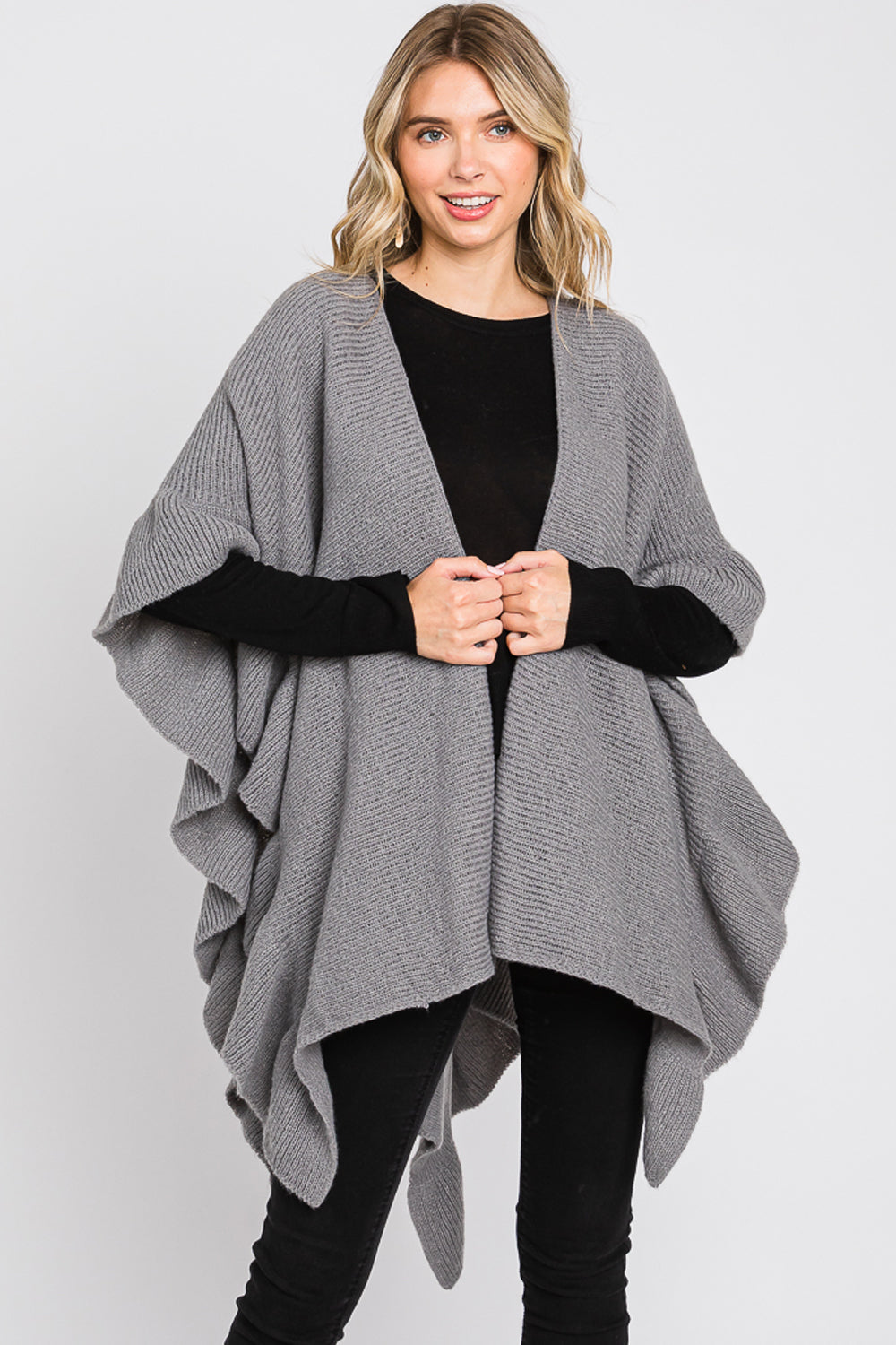 Woman wearing a gray poncho over a black outfit on a white background