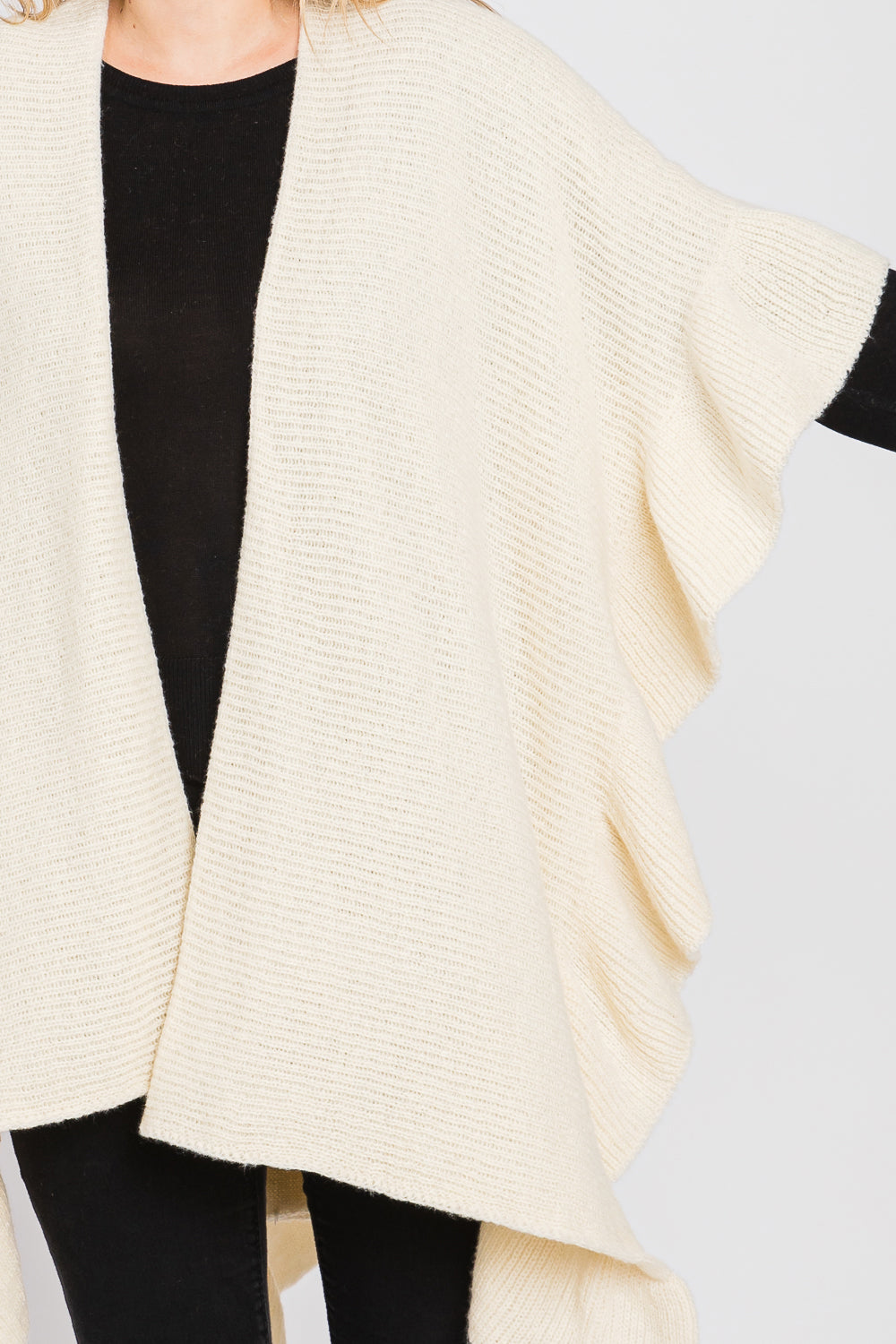 Cream-colored knitted cardigan over a black top on a neutral background