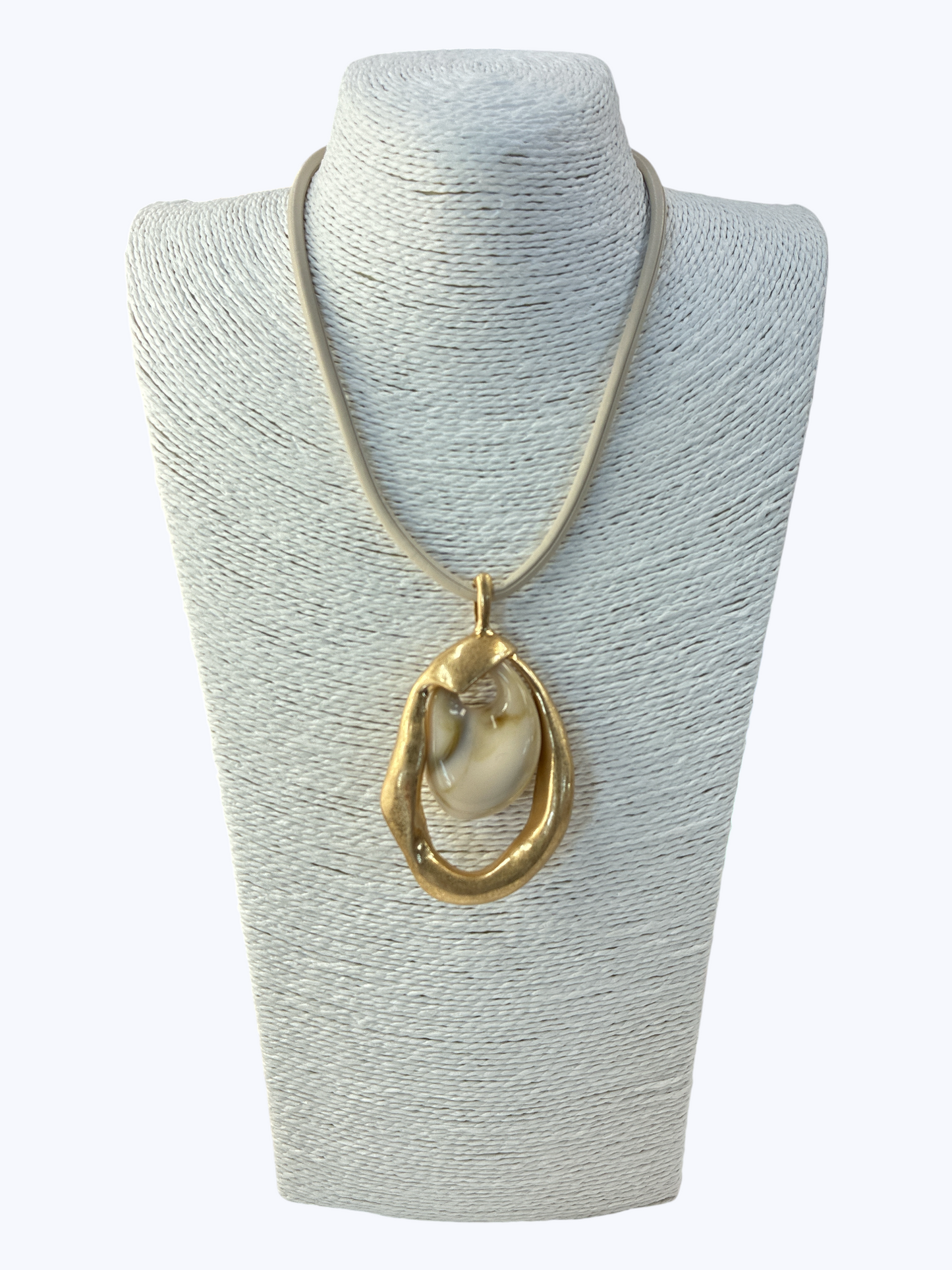 Necklace with a large gold pendant on a gray mannequin bust.