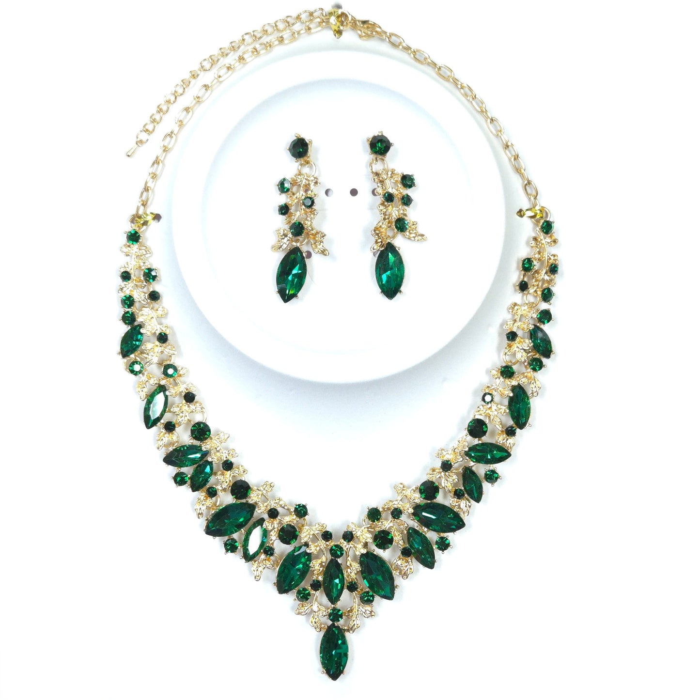 Jewelry set with green gemstones and gold accents on a white background