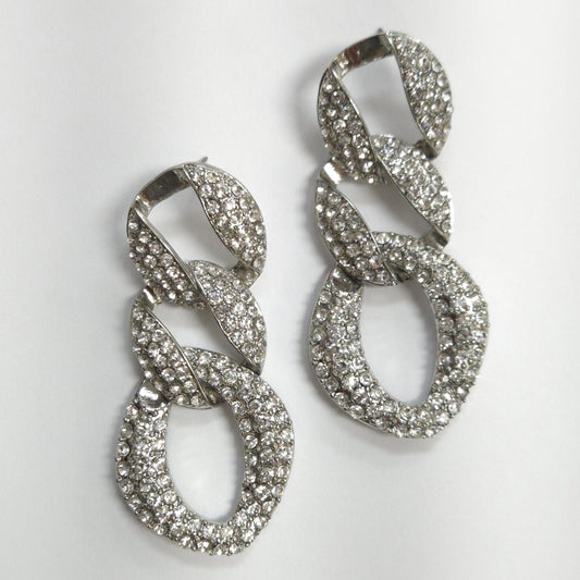 Pair of silver earrings with intricate designs on a light gray background