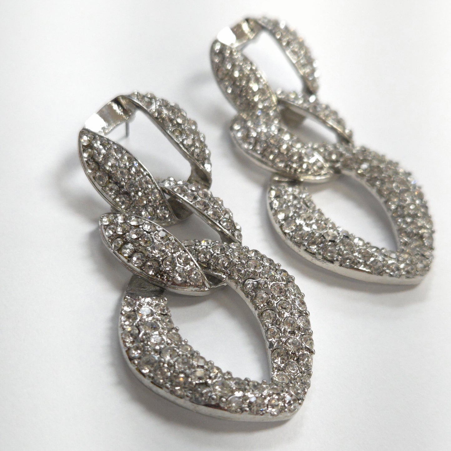 Silver hoop earrings with intricate detailing on a white background