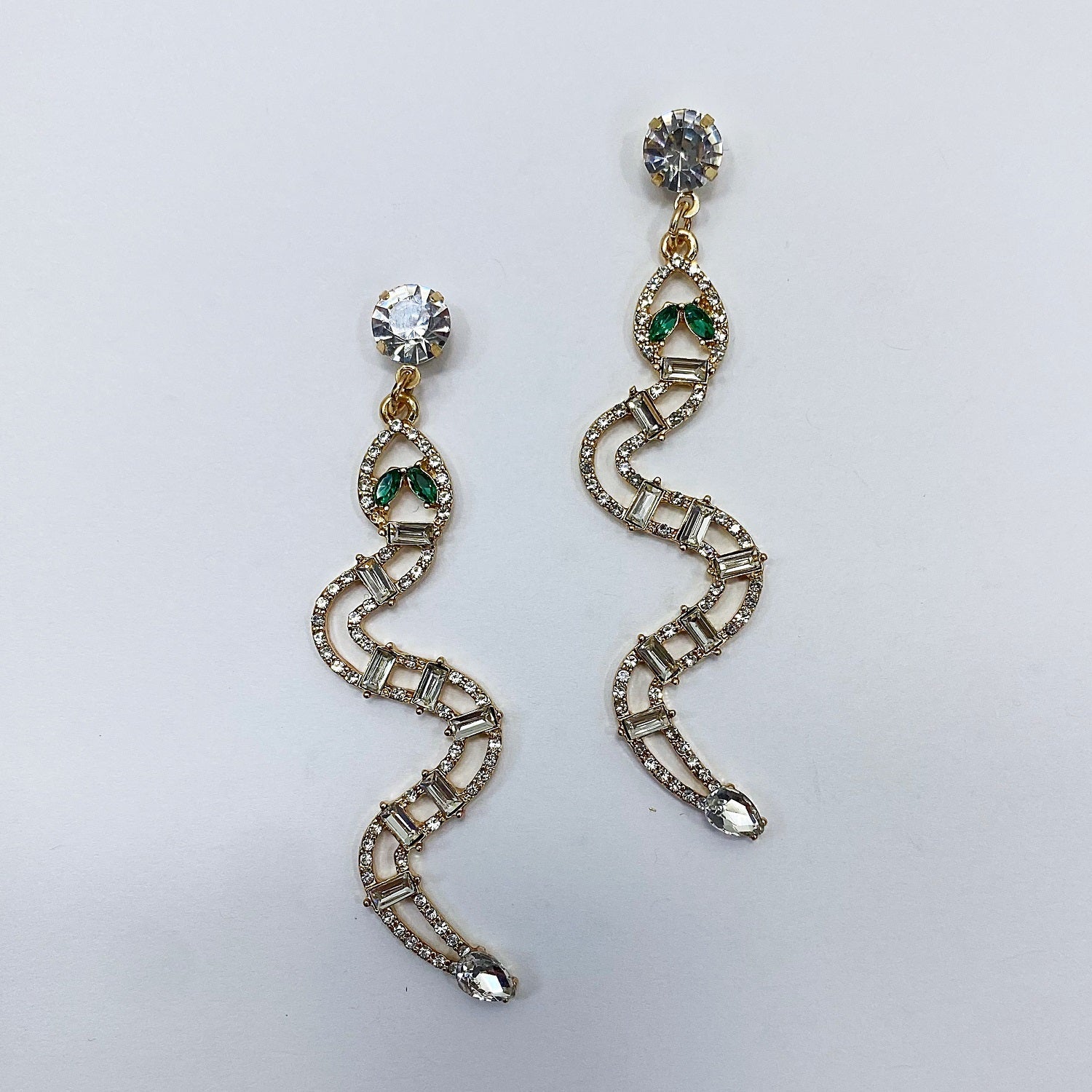 A pair of vintage rhinestone snake-shaped drop dangle post earrings in gold tone with green accents.