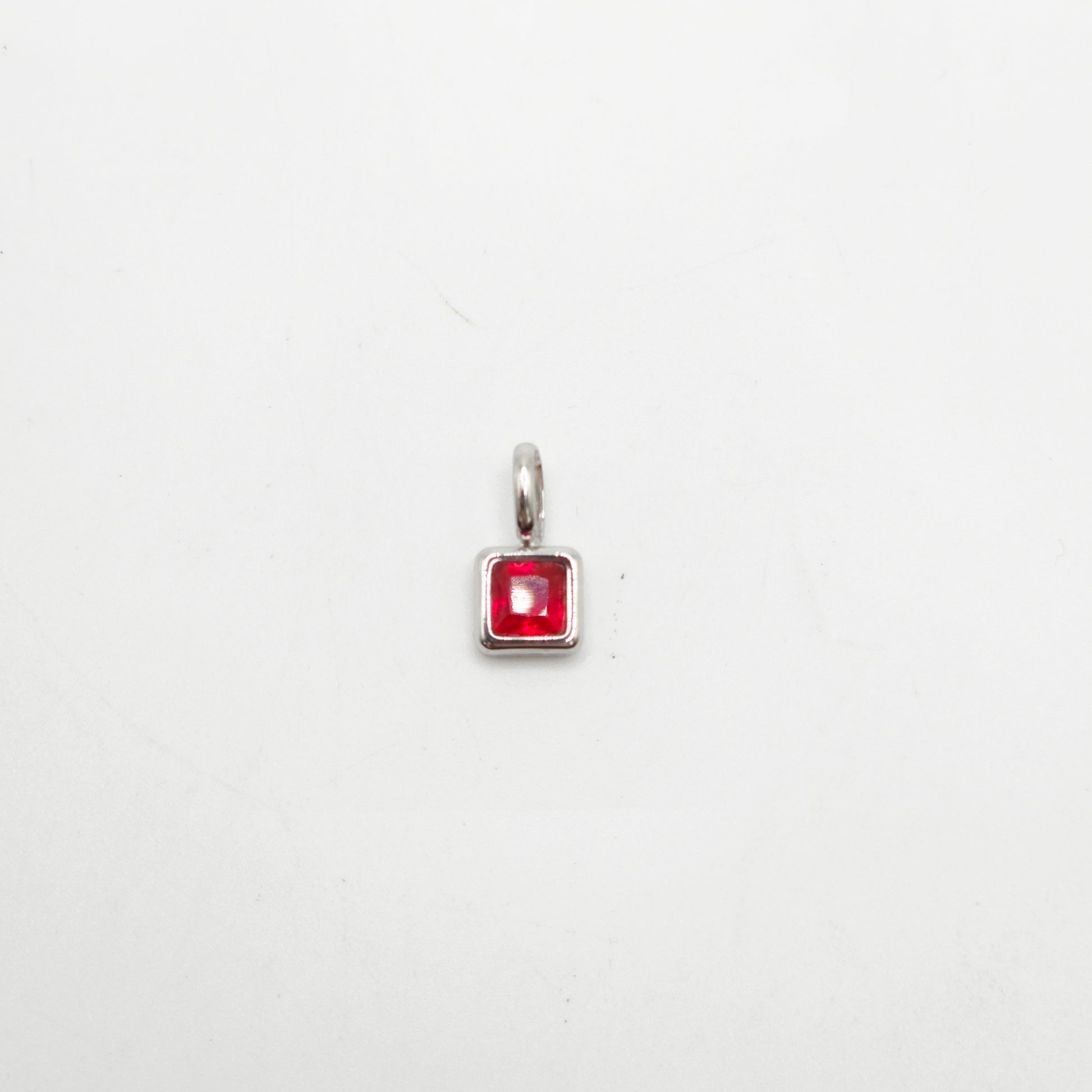 Silver pendant with a red gemstone on a white background