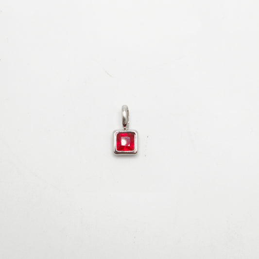 Silver pendant with a red gemstone on a white background