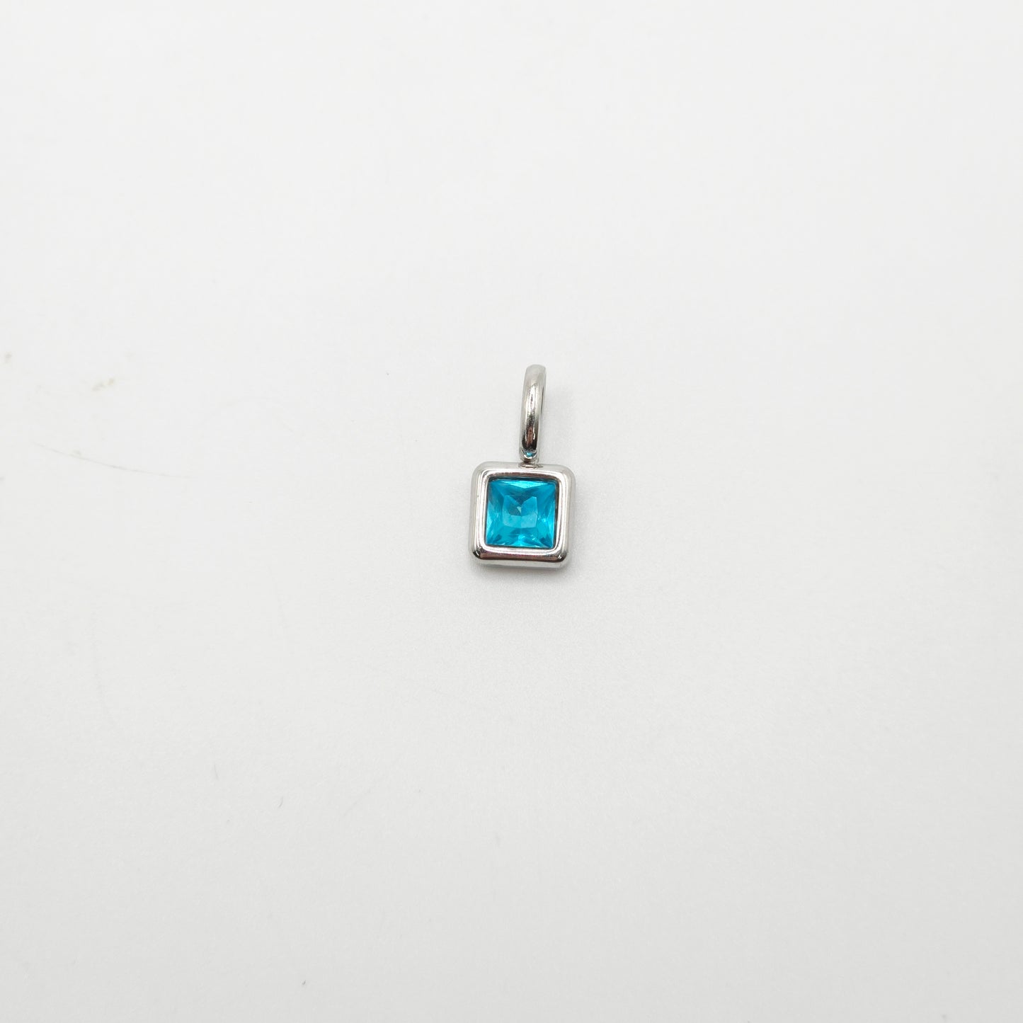 Silver pendant with a blue gemstone on a white background