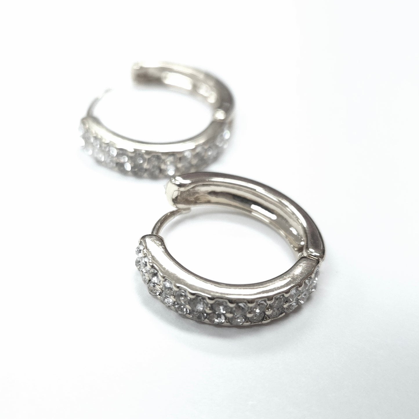 Silver hoop earrings with embedded stones on a white background