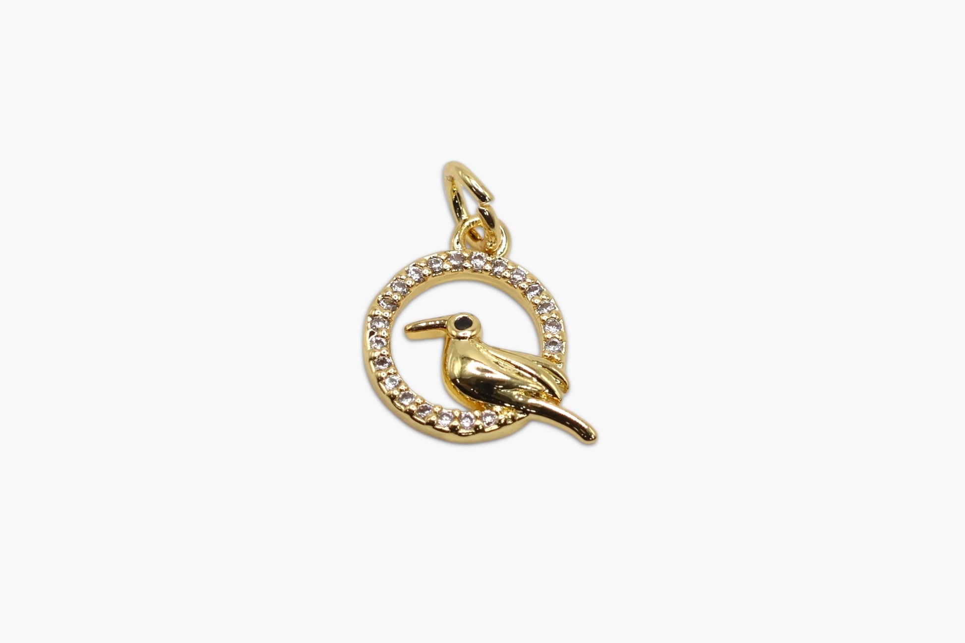 Gold bird charm with circular design on a white background