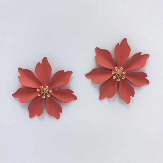 A collection of metal flower design stud style post earrings in various colors displayed on a mannequin ear and against a white background.