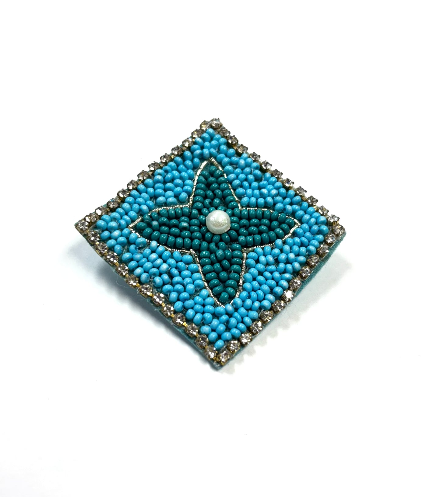 Blue beaded square brooch with a central pearl on a white background