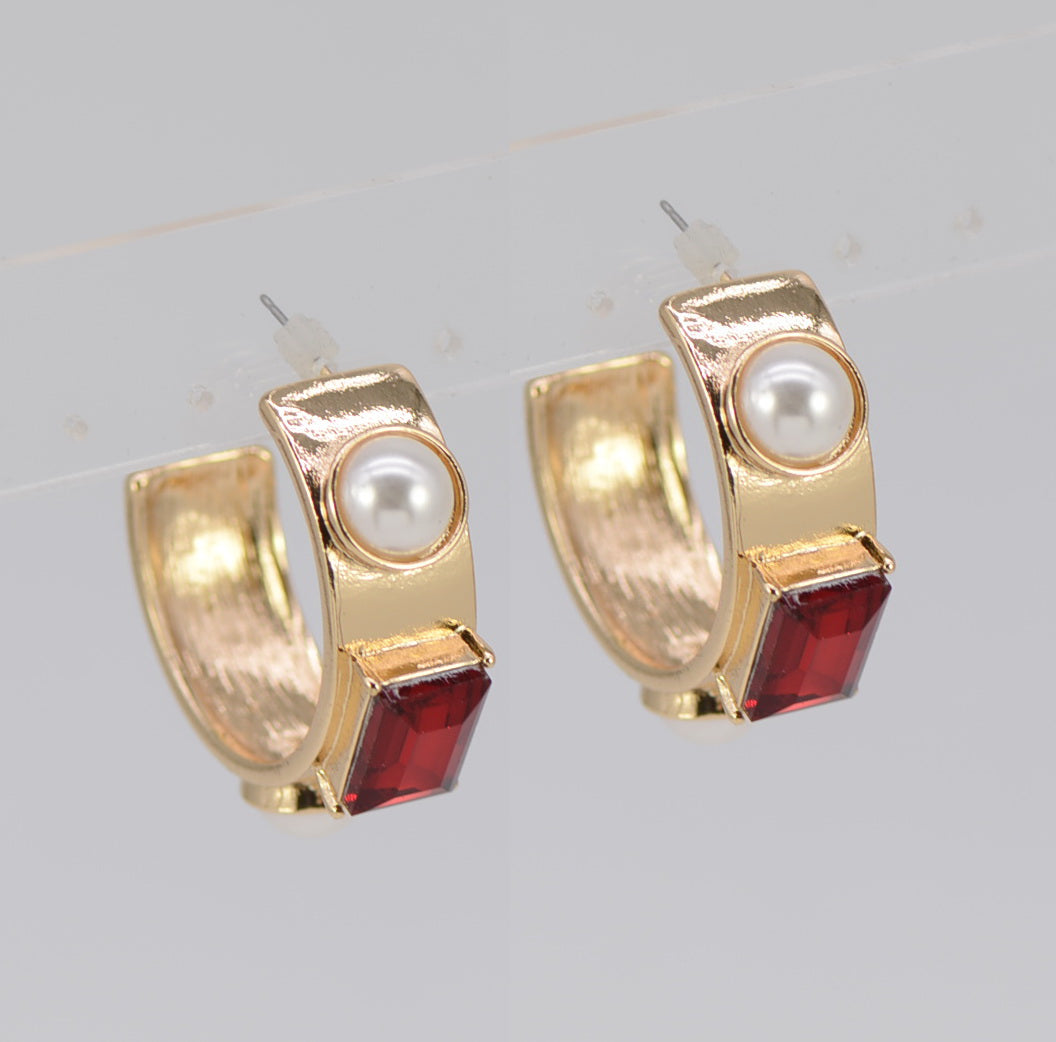 Gold hoop earrings with pearl and red gemstone accents on a light gray background
