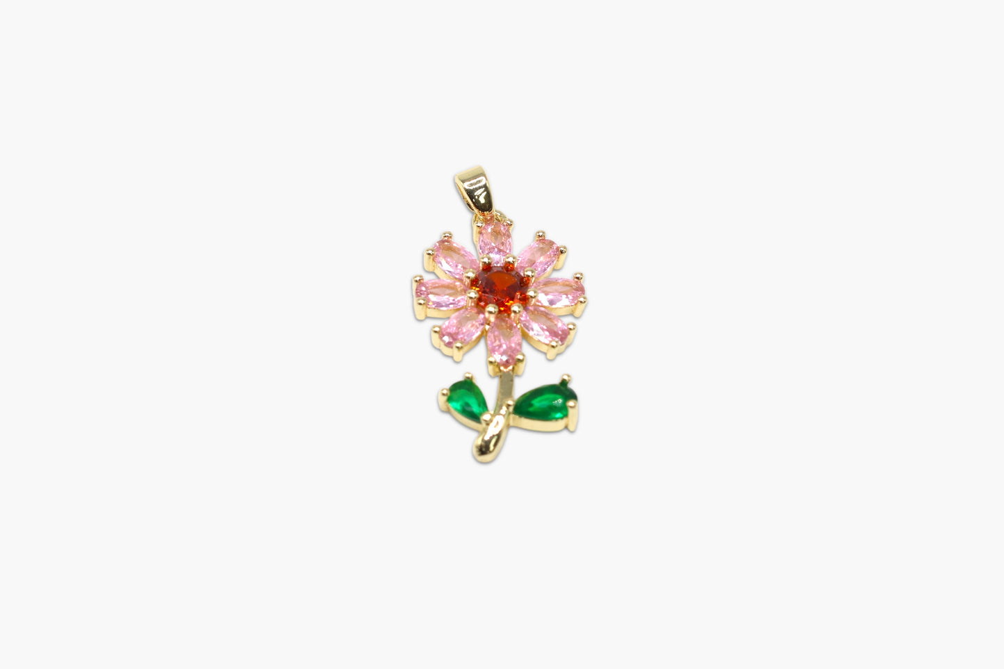 Gold pendant with pink gemstone and green leaves on a white background