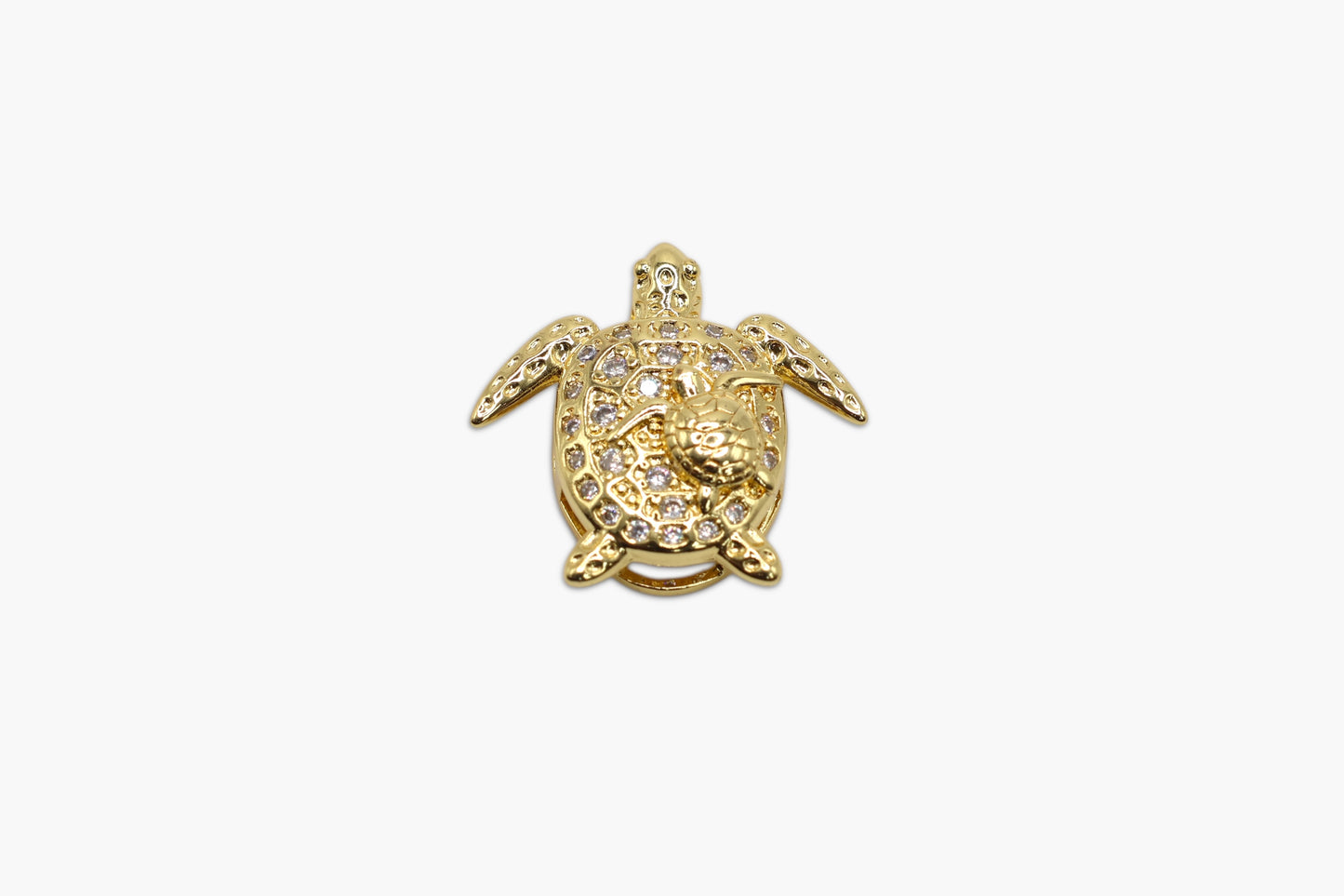 Gold turtle-shaped pendant with embedded stones on a white background