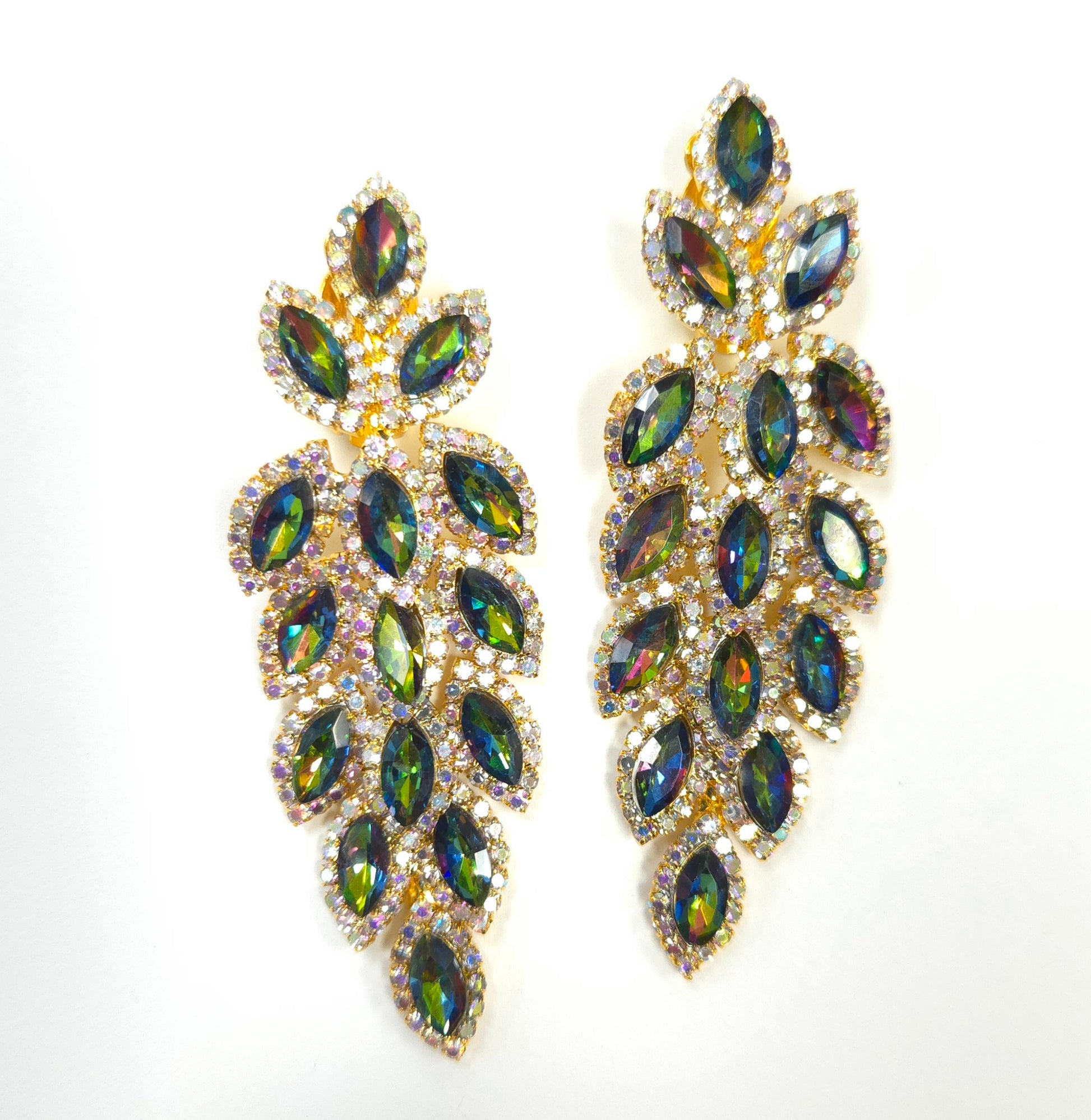 Pair of ornate earrings with green gemstones on a white background