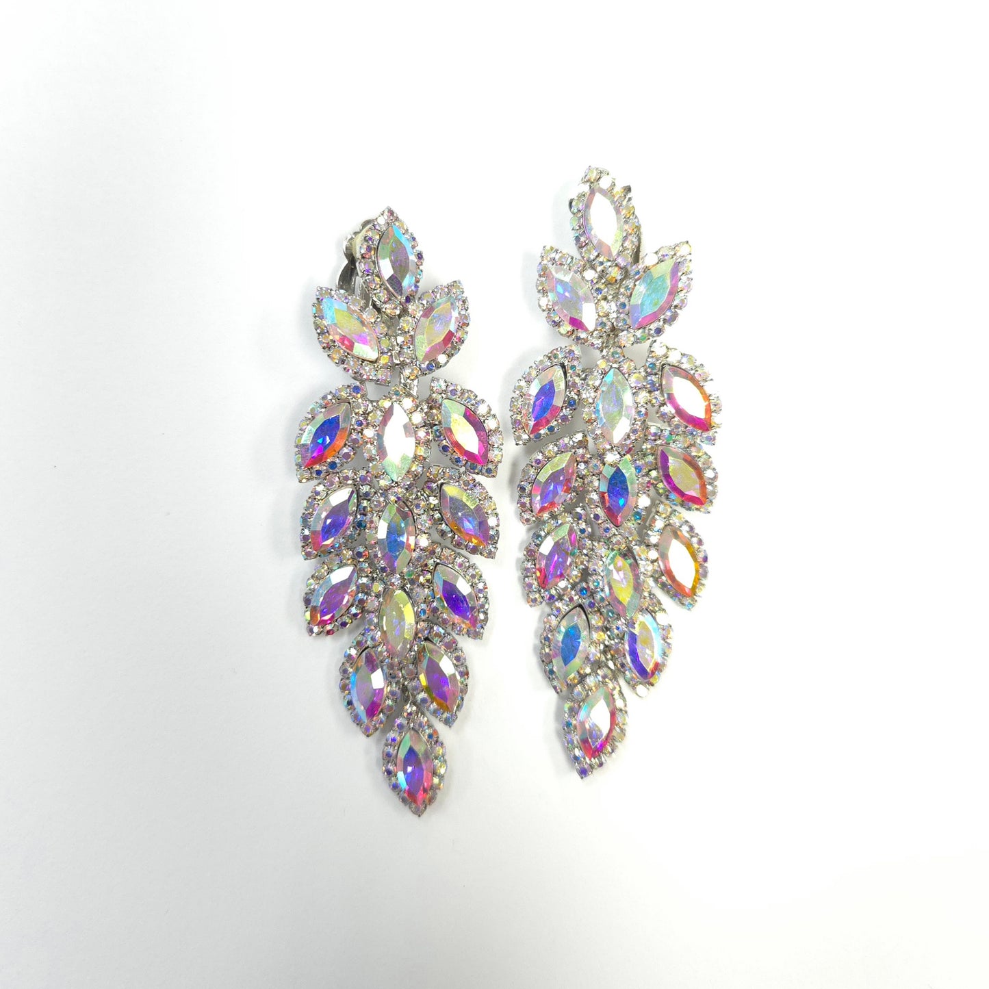 Pair of ornate earrings with multicolored gemstones on a light gray background