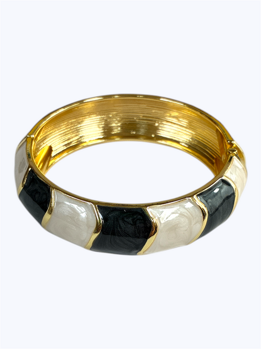 Gold bracelet with black and white pattern on a white background