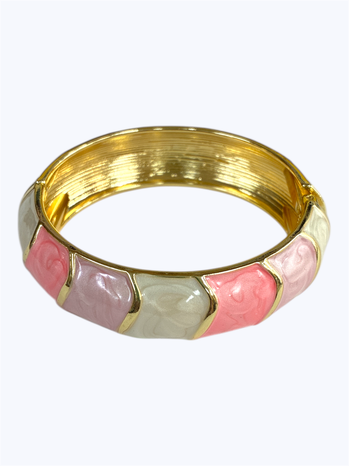Gold bangle with pink and white ceramic sections on a white background