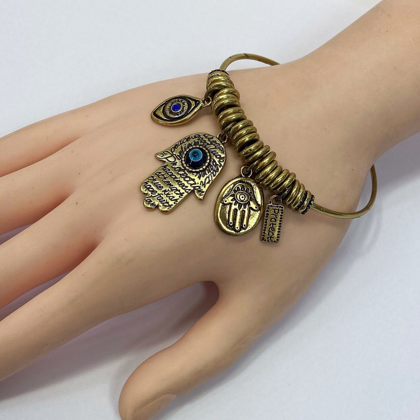 Open cuff bracelet featuring evil eye, hamsa hand, and protection charms with decorative metal accents