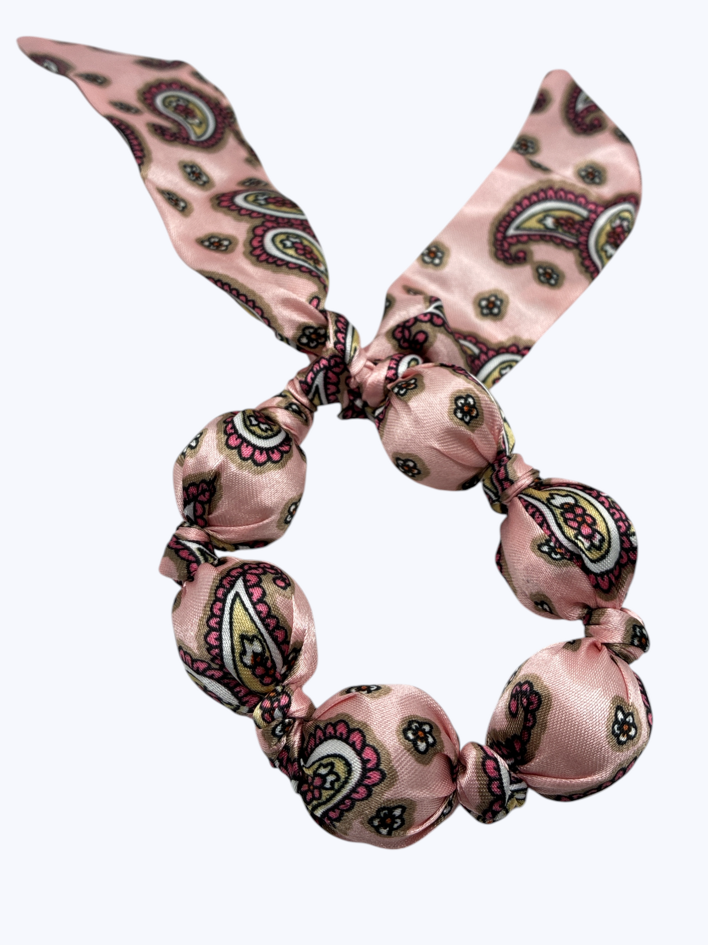 Pink paisley patterned hair tie on a white background