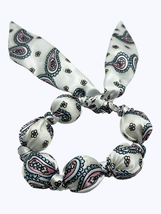 White hair tie with blue and pink paisley pattern on a white background