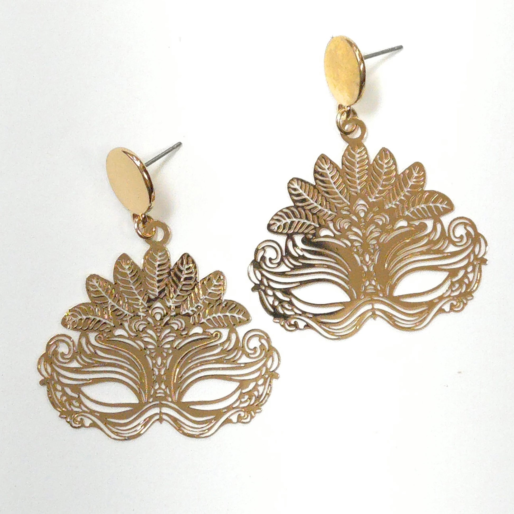 Gold mask-shaped earrings on a white background