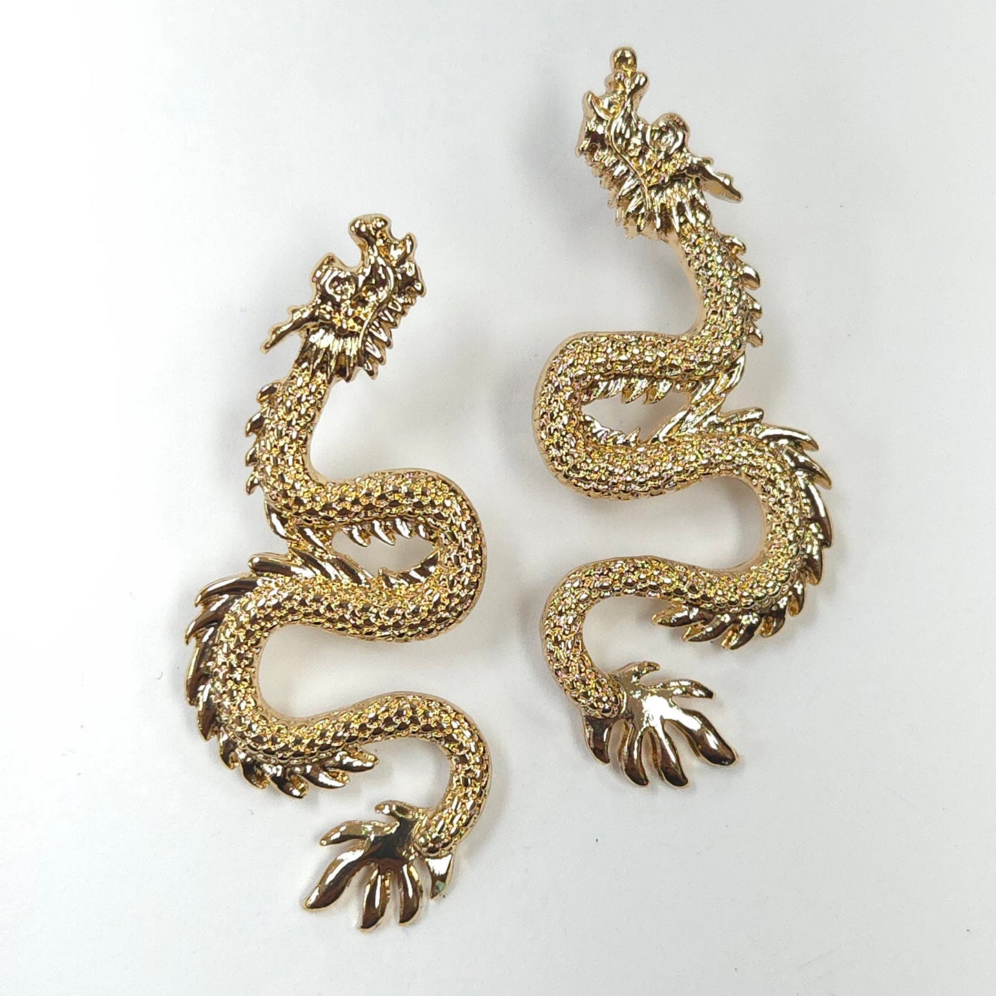 Gold dragon-shaped earrings on a white background