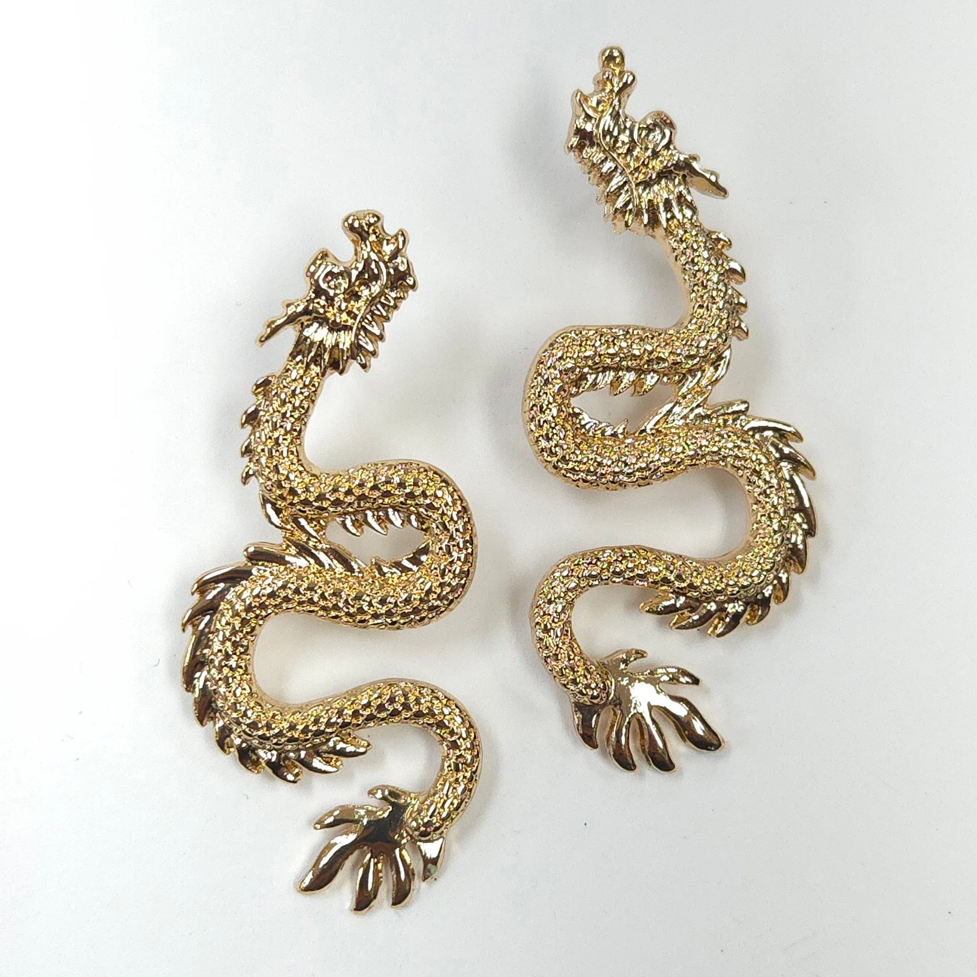 Gold dragon-shaped earrings on a white background