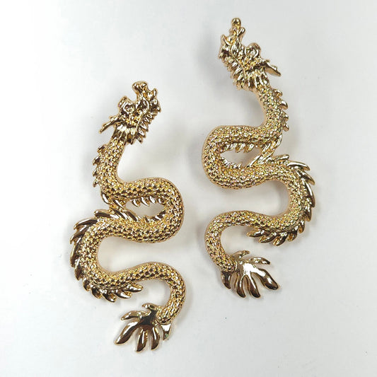 Gold dragon-shaped earrings on a white background